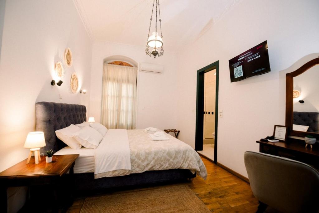 A room with a grey velvet headboard, pendant lamp and en-suite bathroom beyond