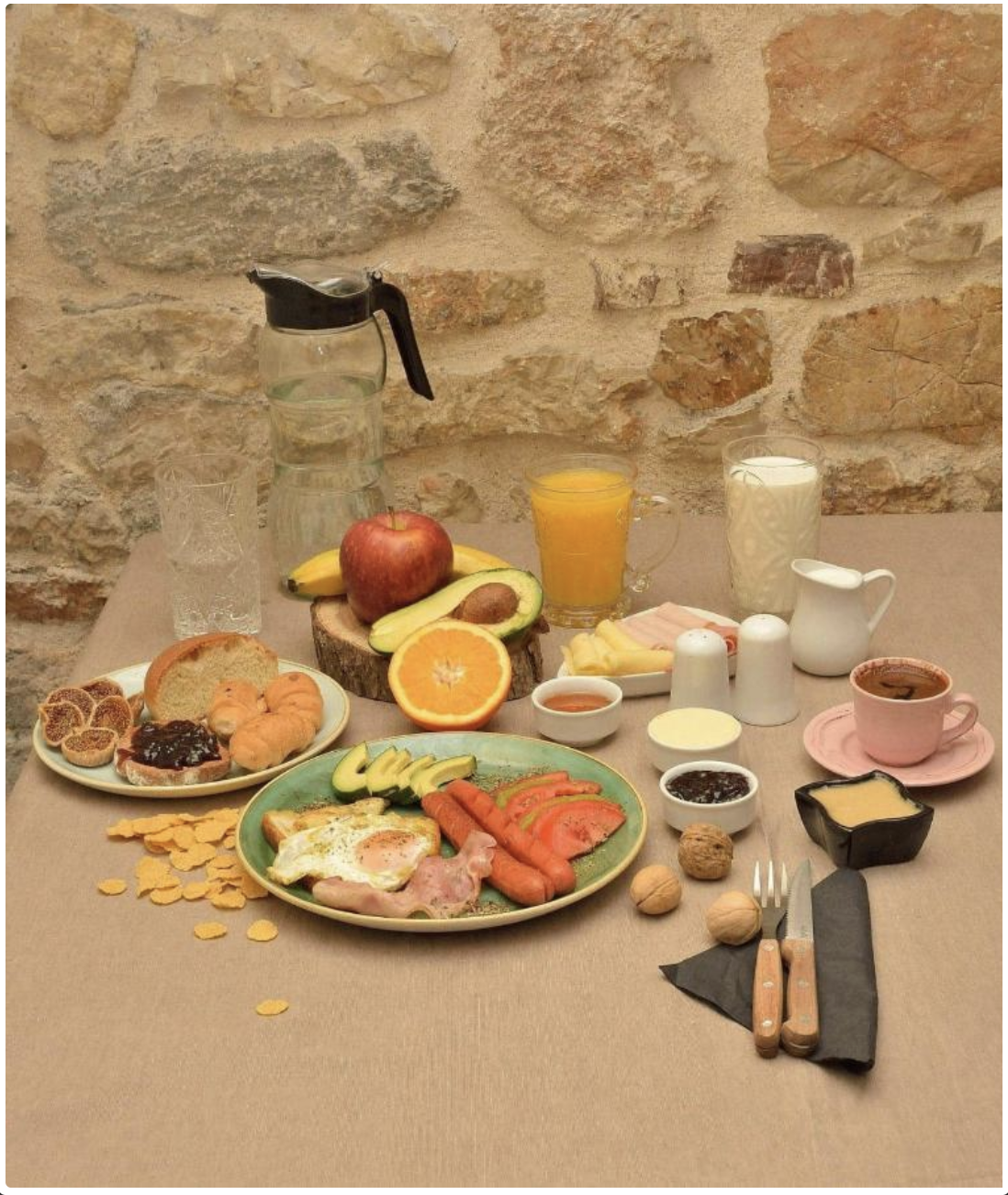 A traditional Greek breakfast laid out with eggs, sausages, fruit, cheeses and fresh bread
