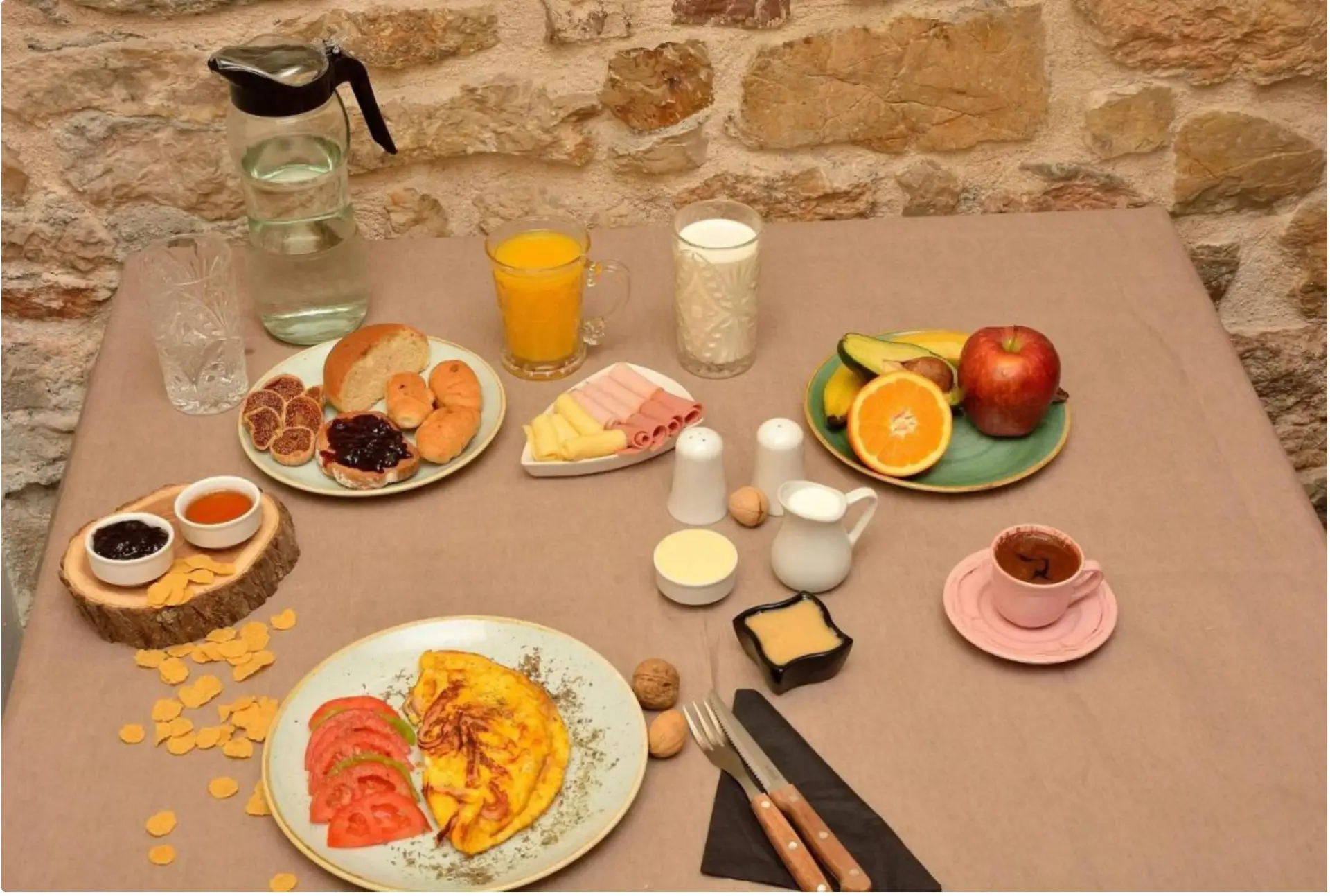 A full breakfast spread in the courtyard with omelette, fresh fruit, juices, jams and Greek coffee