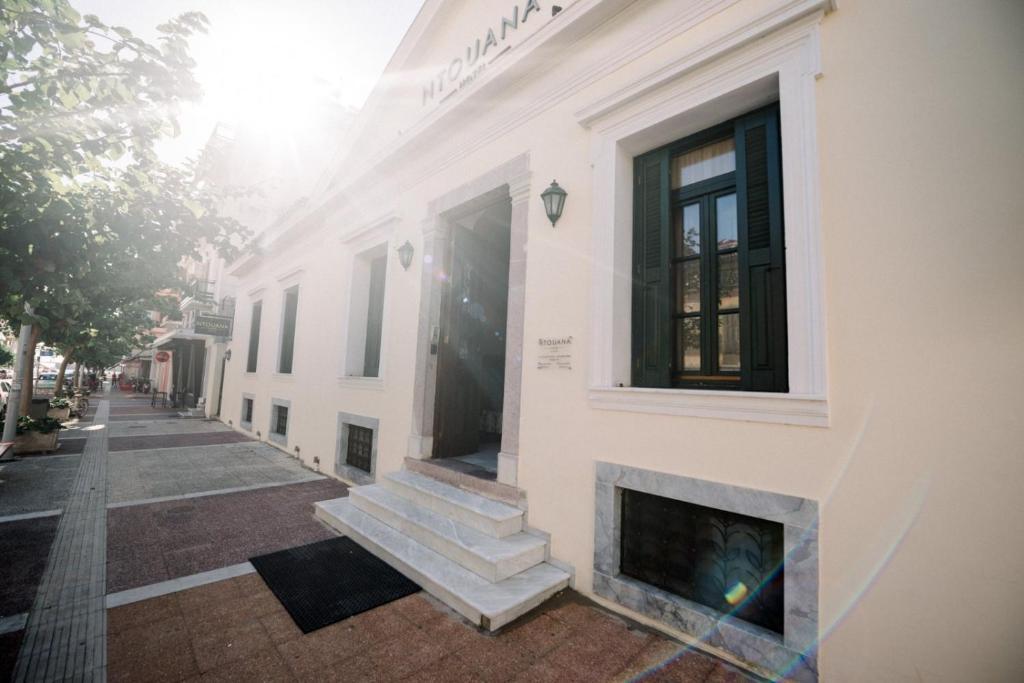 Marble steps and the sunlit side entrance of Ntouana Hotel on a quiet Kalamata street