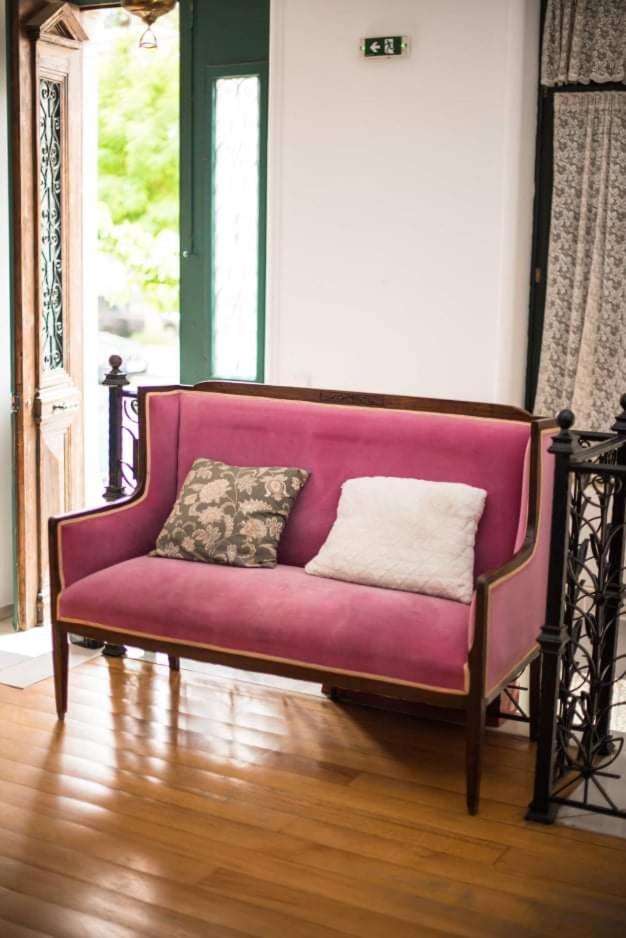 An antique rose velvet sofa by the open door of the entrance parlour