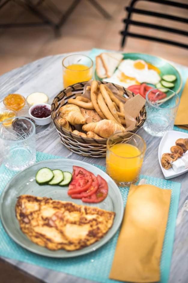 A breakfast table in the courtyard with omelette, fresh bread, jams and orange juice