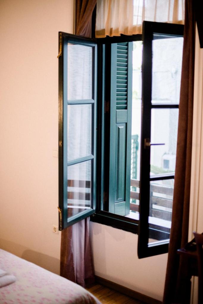 Green wooden shutters open from inside a guest room on a bright morning