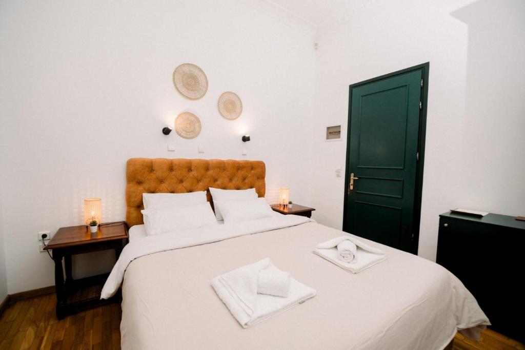 A bright room with a tan buttoned headboard, woven wall discs and folded towels on the bed