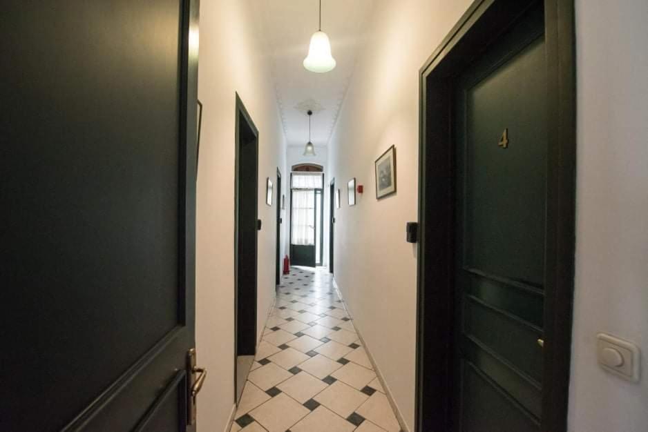 The chequered corridor of the house with tall dark-green doors and pendant lamps