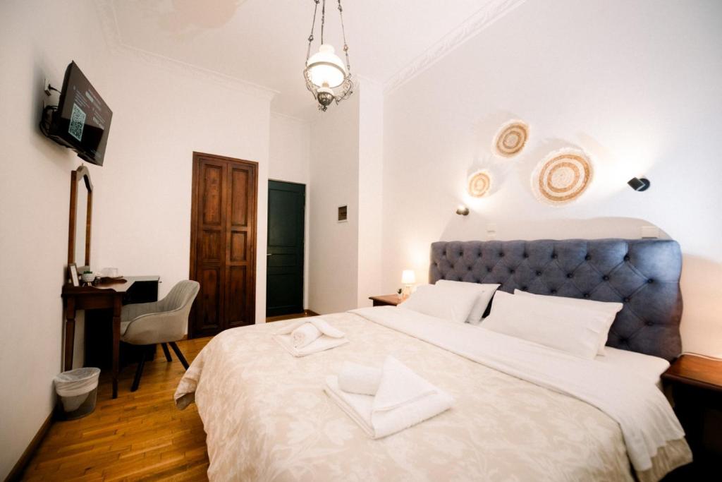 A room at Ntouana with a deep blue tufted headboard, wooden floor, writing desk and mirror