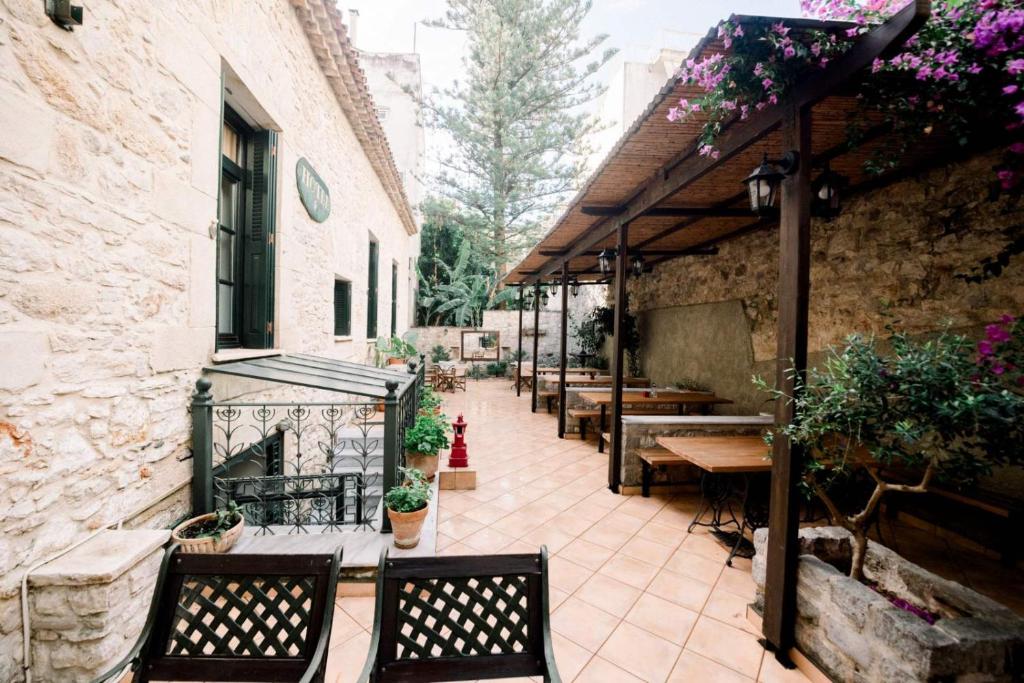 The courtyard of Ntouana under a wooden pergola draped in bougainvillea, with stone walls and lanterns